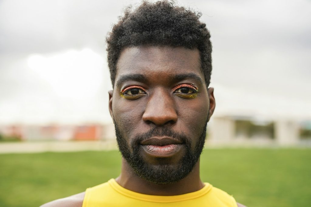 Young gay african man with make looking at camera at city park - Focus on face